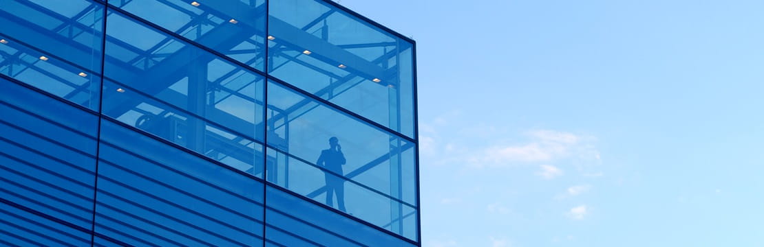 Exterior view of a businessman standing alone in the corner of office building.